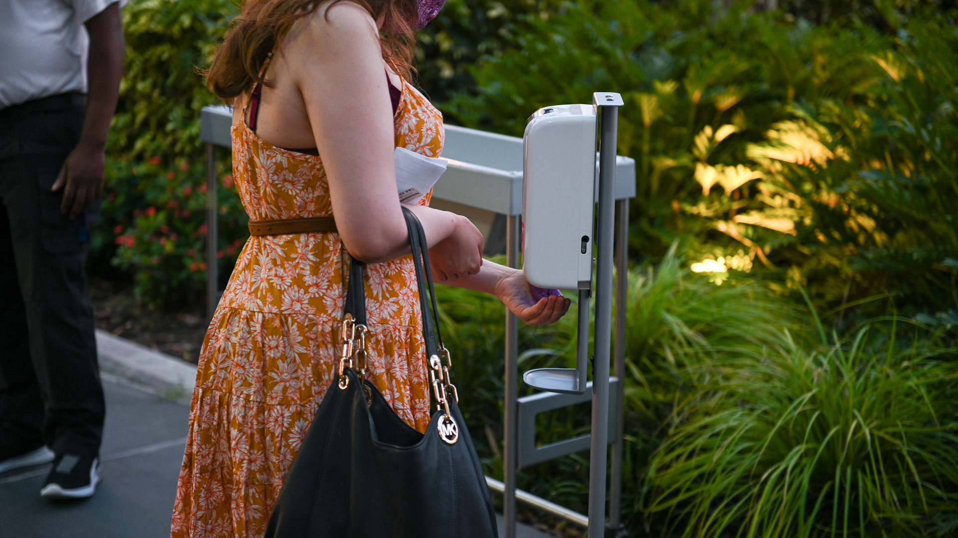 Guest using hand sanitizer machine outside the Straz.