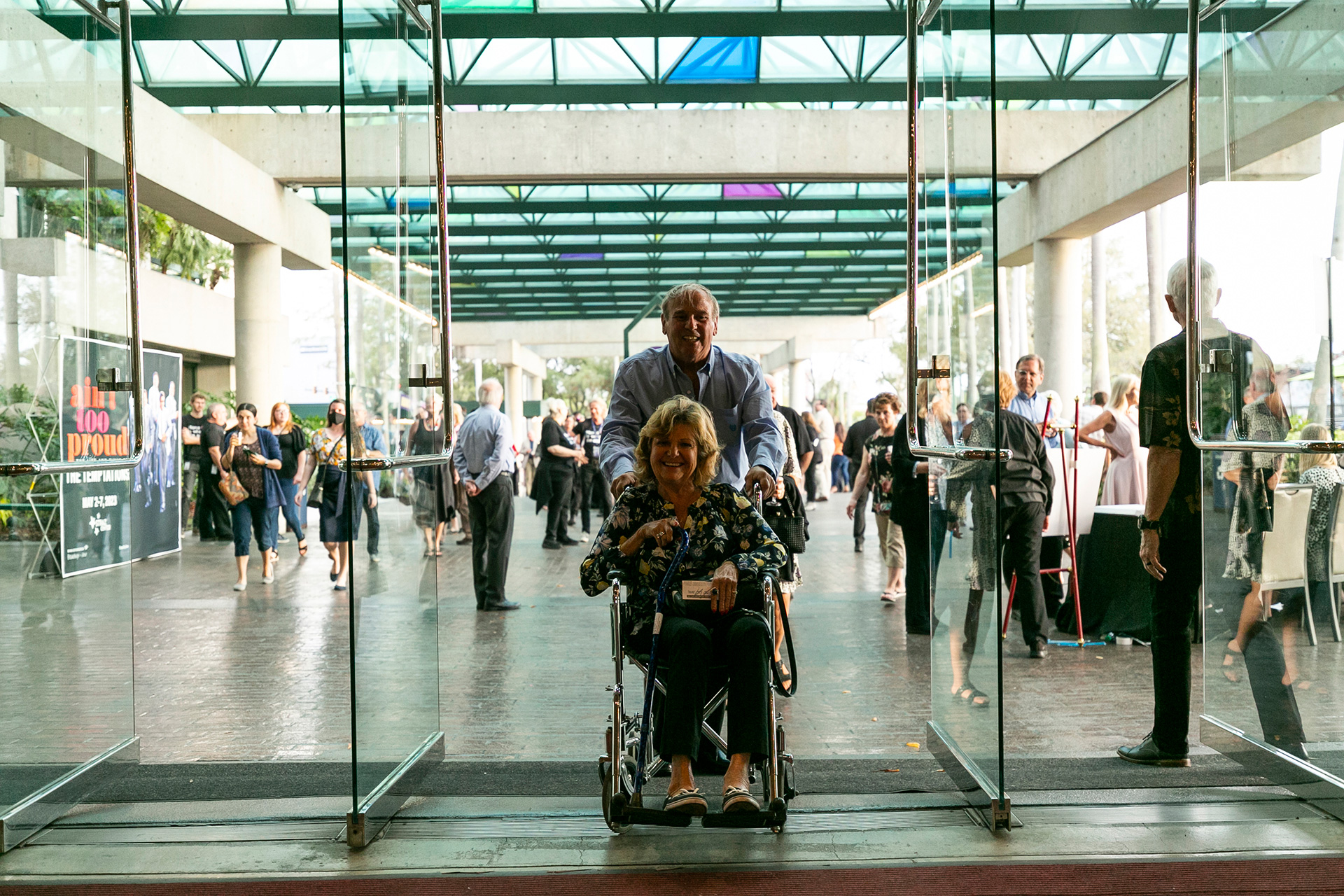 male pushing female on wheelchair at at theater entrance.