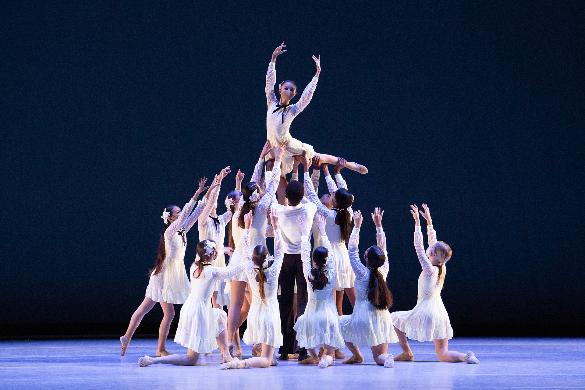 Ballet ensemble performing a dance routine on stage.