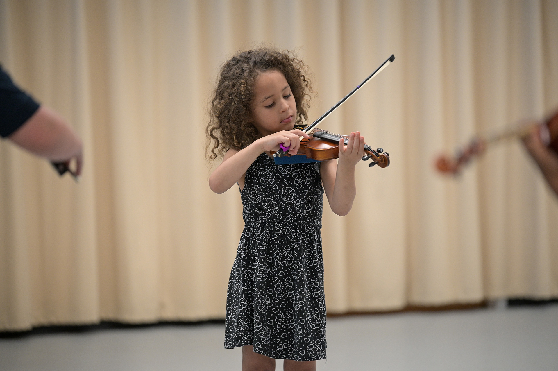 Young violinist performing against a beige curtain backdrop.