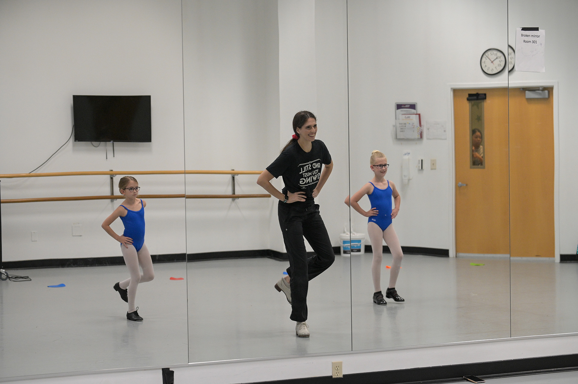 Ballet instructor practicing with two students in a ballet studio.