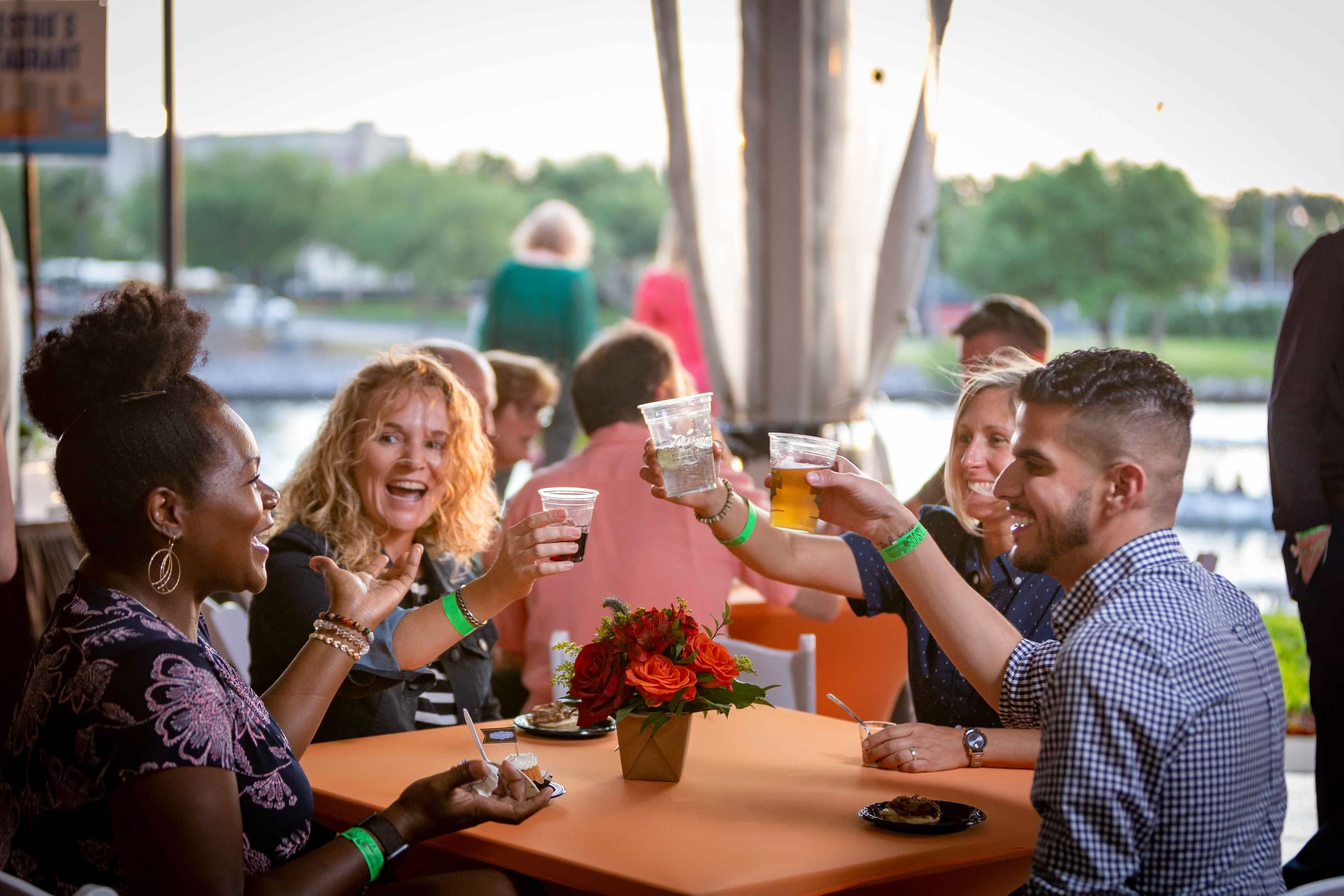 Guests sitting at outdoor table toasting each other.