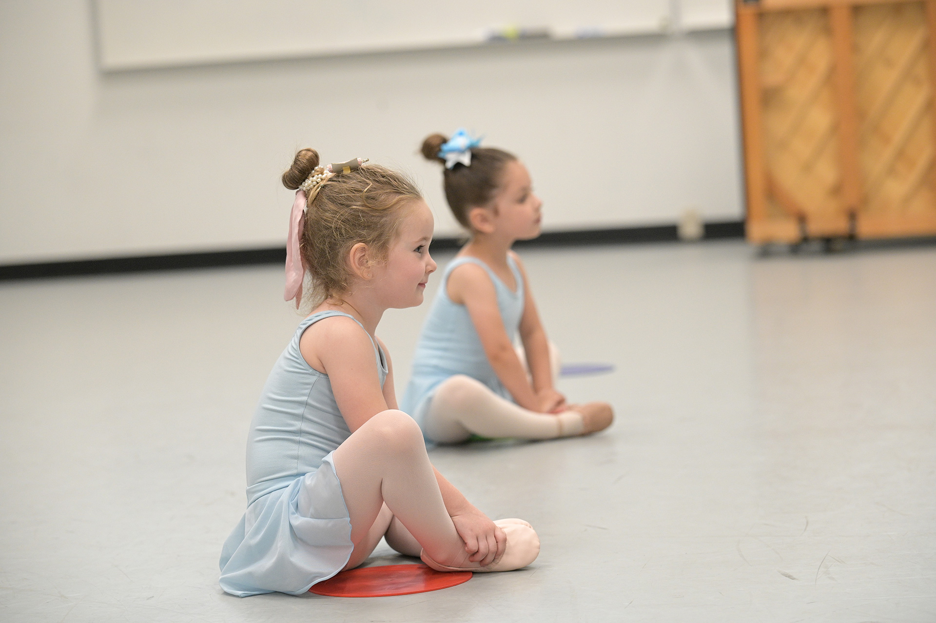 Patel students sitting on studio floor in dance costumes.